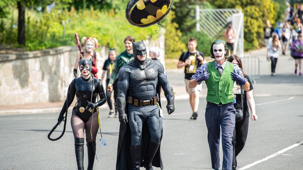 Ulicą obok MTP idą trzy osoby przebrane za postacie znane z uniwersum "Batmana" - jest wśród nich Kobieta Kot, Batman i Joker. Jedna z postaci niesie balon ze znakiem Batmana.