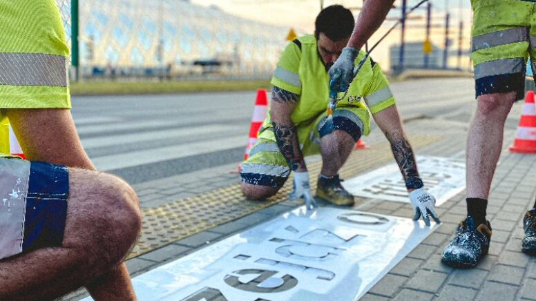 Men creating a sign "Go Offline" near a walkway.
