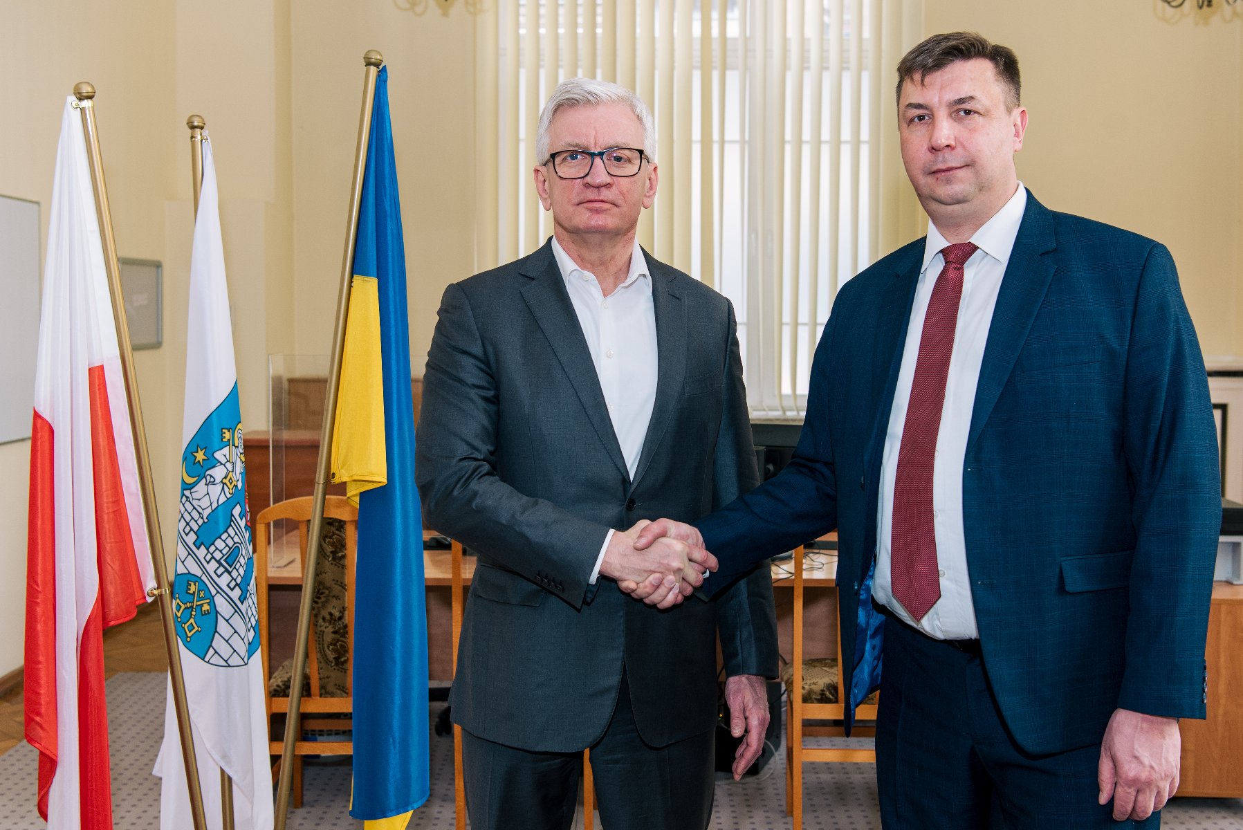 The photo shows the Mayor of Poznań and the Ukrainian Consul shaking hands, next to the flags of both countries - grafika artykułu