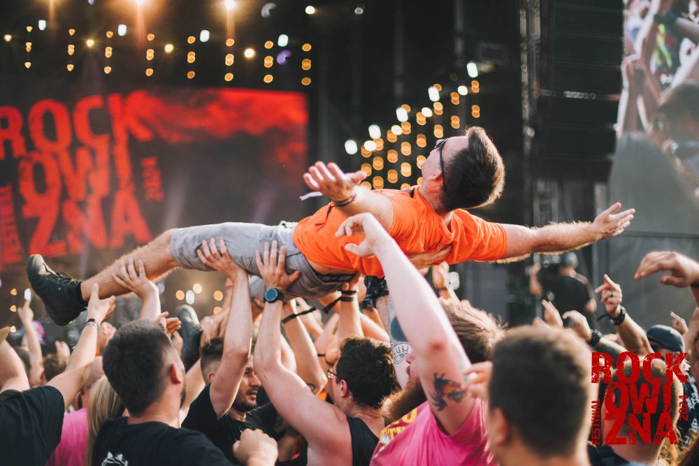 Festiwal Rockowizna, fot. Anna Migda Chłopak w pomarańczowym T-shircie niesiony przez tłum na rękach.