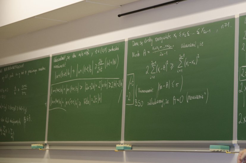 Poznańskie Koła Olimpijskie z Matematyki Grafika przedstawia tablicę szkolną z zapisanymi wzorami z matematyki