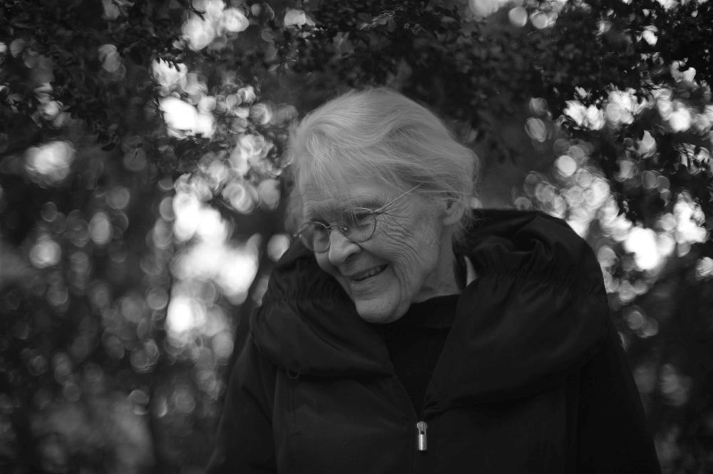 Krystyna Miłobędzka (1932-2025) fot. Filip Łepkowicz kobieta w podeszłym wieku, ubrana na czarno, nosi okulary, siwe włosy spięte do tyłu, uśmiecha się
