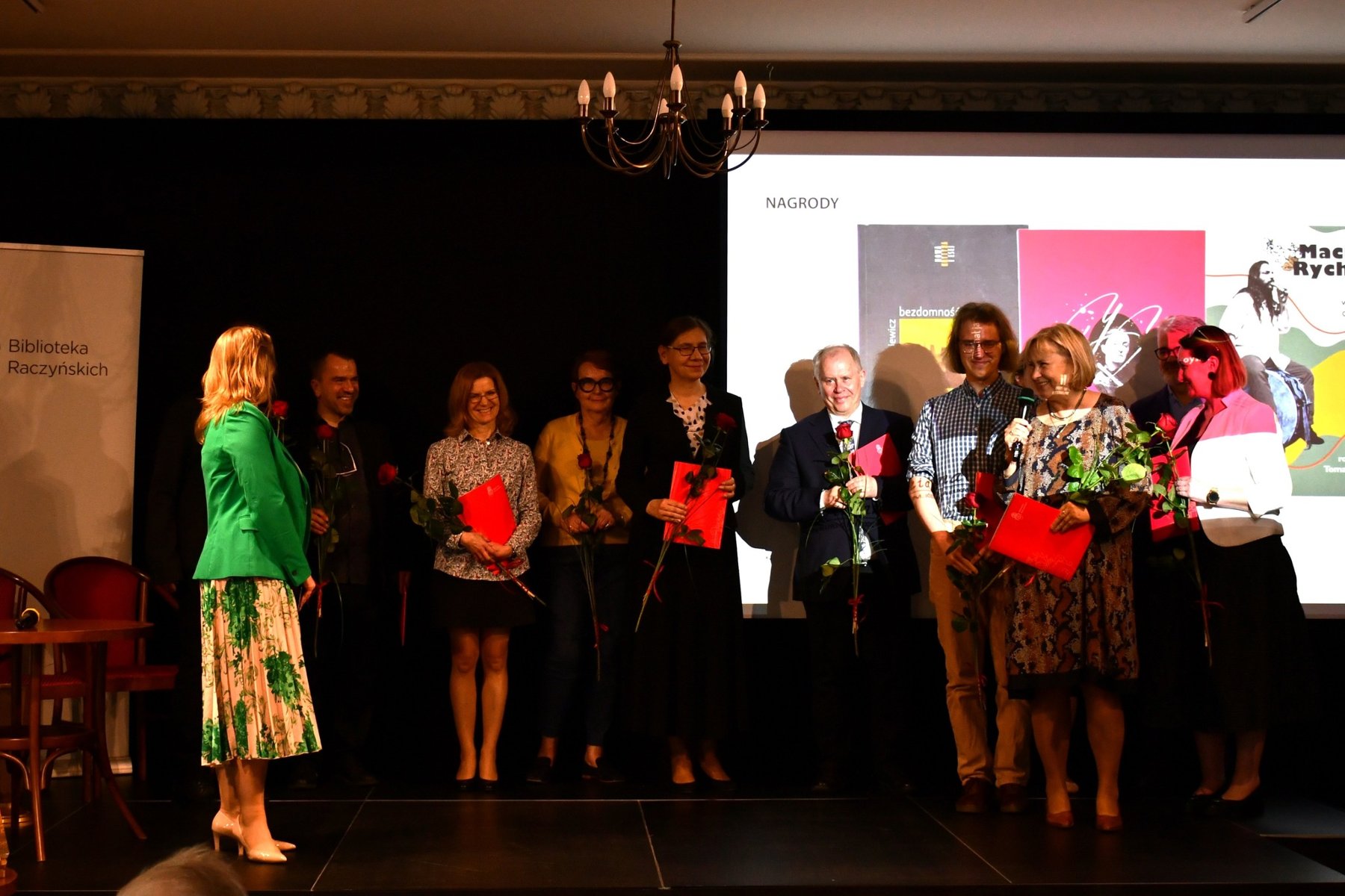 Posnaniany 2024 - laureaci Ludzie z dyplomami za najlepsze książki o Poznaniu. Kilkanaście osób stoi na scenie.