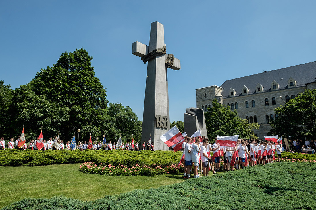 Młodzież z biało-czerwonymi flagami. Przed pomnikiem.