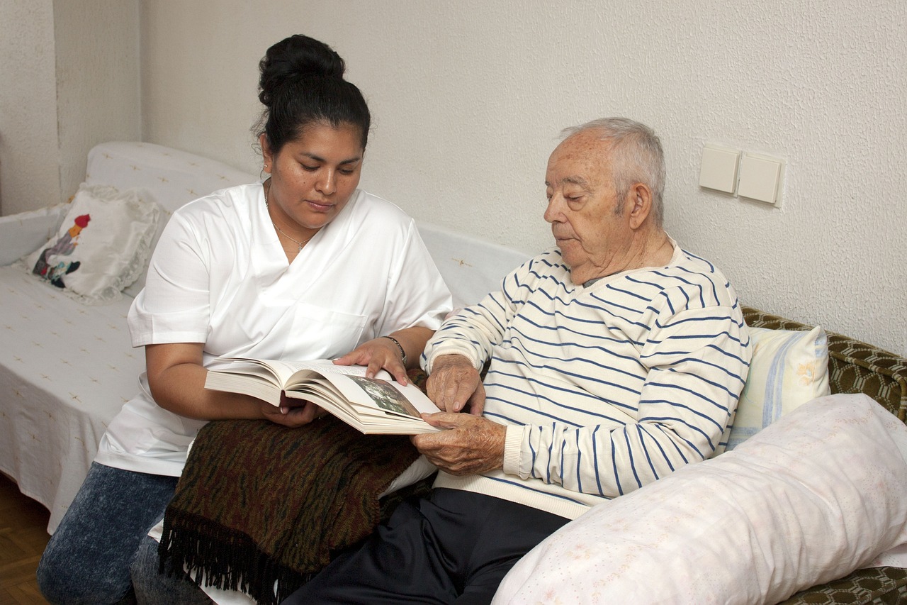 Na zdjęciu kobieta w białym fartuchu pokazuje książkę starszemu mężczyźnie - grafika artykułu
