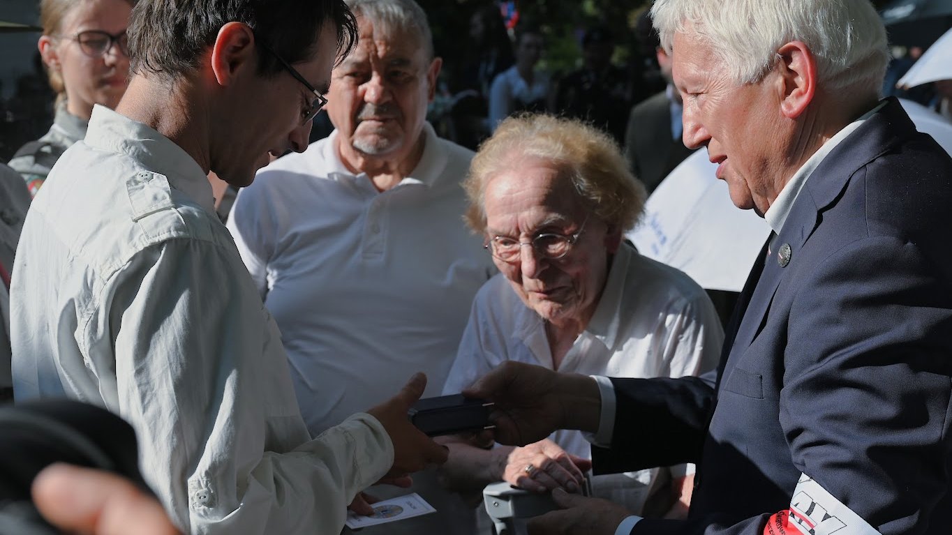 Na zdjęciu starszy mężczyzna wręcza młodszemu odznaczenie