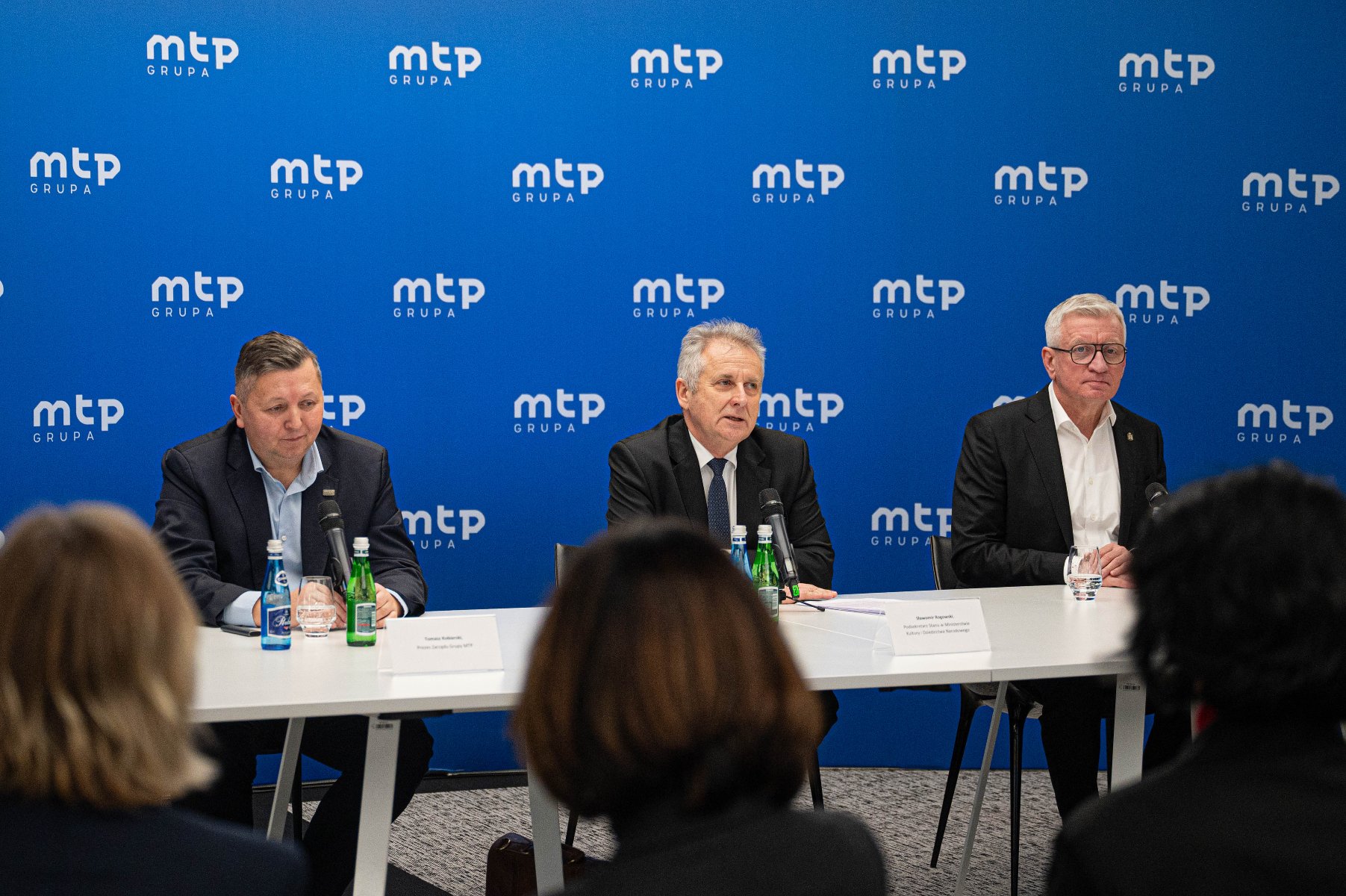 Na zdjeciu trzej męzczyźni za stołem konferencyjnym, za nimi ścianka z napisem: grupa mtp - grafika artykułu