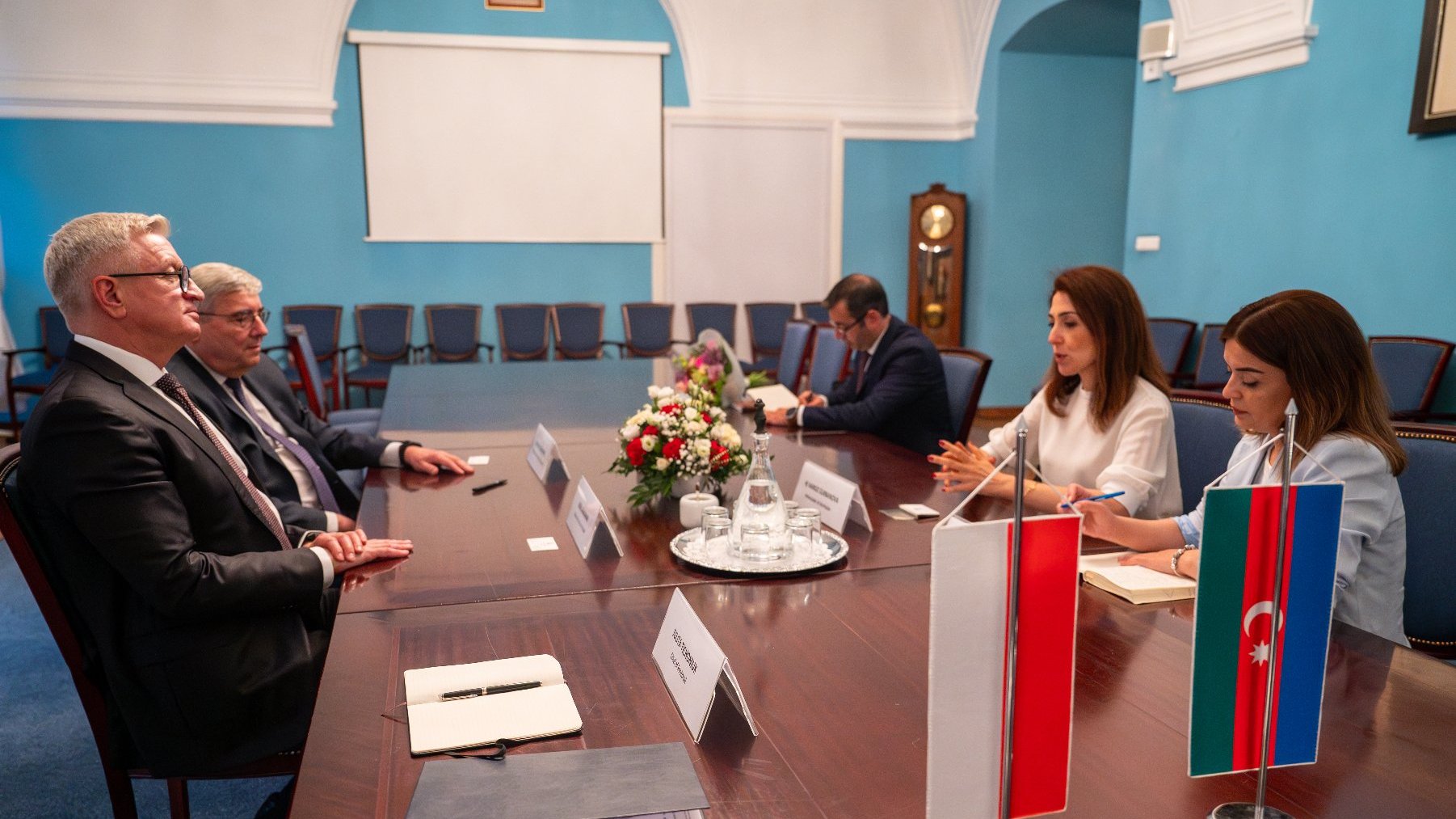 Na zdjęciu kilka osób przy stole, na pierwszym planie flagi Polski i Azerbejdżanu