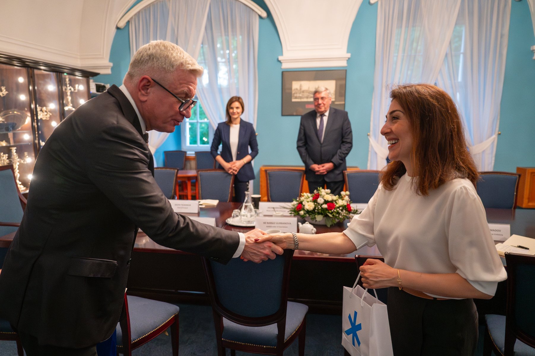 Na zdjęciu prezydent Poznania podający dłoń ambasador, w tle dwie osoby, w tym przewodniczący rady miasta - grafika artykułu
