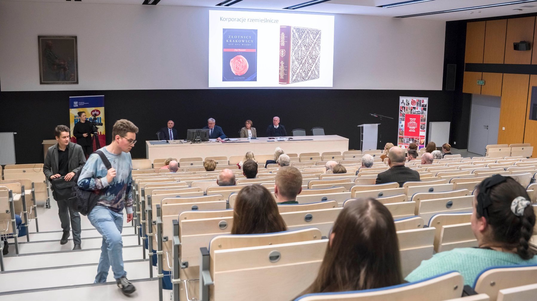 Na zdjęciu sala konferencyjna. Ludzie siedzą na krzesłach i słuchają wykładów.