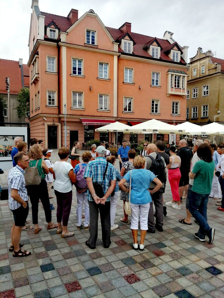 Zdjęcie przedstawia grupę kobiet i mężczyzn stojących na ulicy. - grafika artykułu