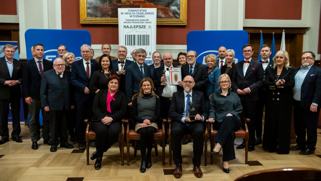 Ludzie siedzący na krzesłach będący laureatami konkursu "Najlepsi w Polsce". Część ludzi trzyma dyplomy. W centralnym miejscu siedzą dyrektor Wydawnicta i jej zastępczyni.