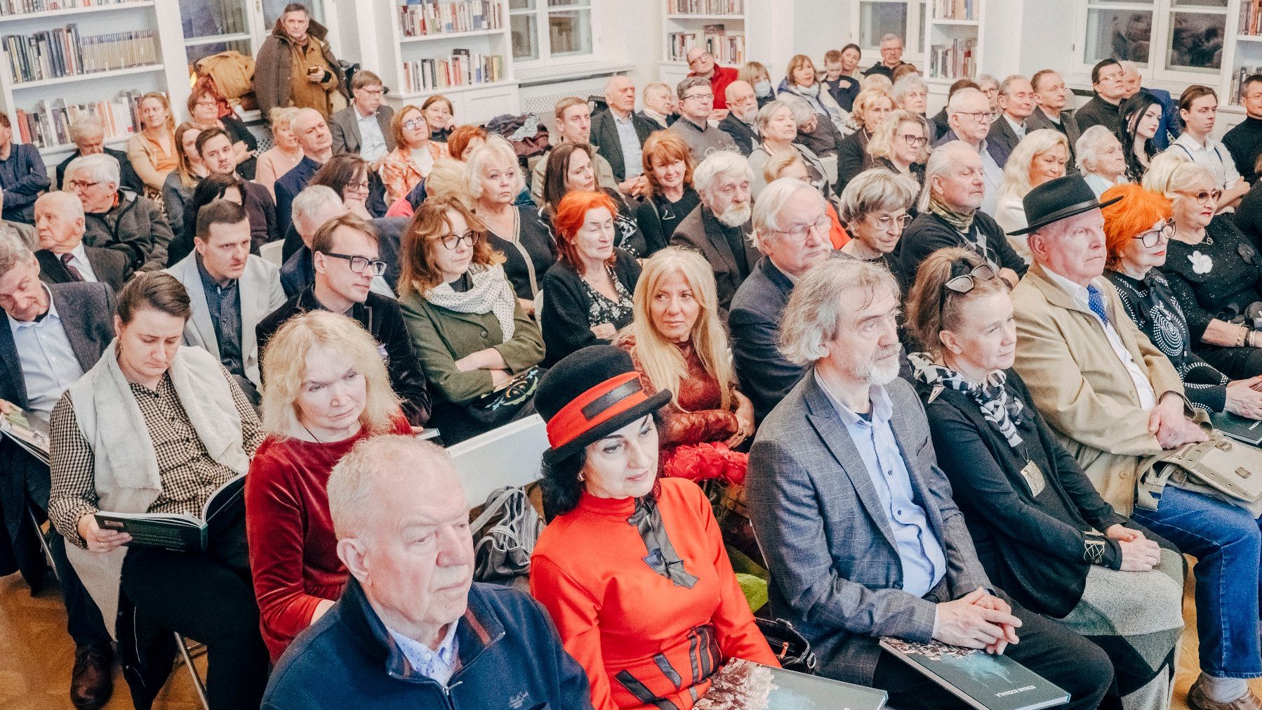 Licznie zgromadzona publiczność. Kilkadziesiąt ludzi siedzących na krzesłach.