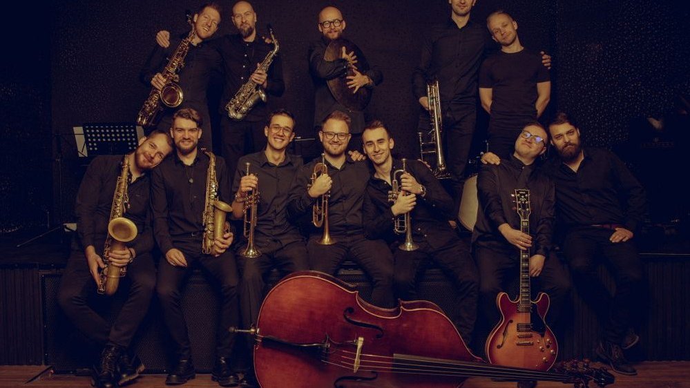 Męska orkiestra pozuje ze swoimi instrumentami muzycznymi. Wszyscy ubrani są na czarno.