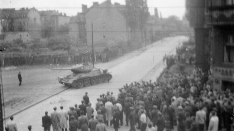 Ulica Kochanowskiego 28 czerwca 1956 roku godzina 13. Na ulicę od strony ul. Dąbrowskiego wjeżdża czołg T34 i jedzie przez pusty plac po lewej stronie.