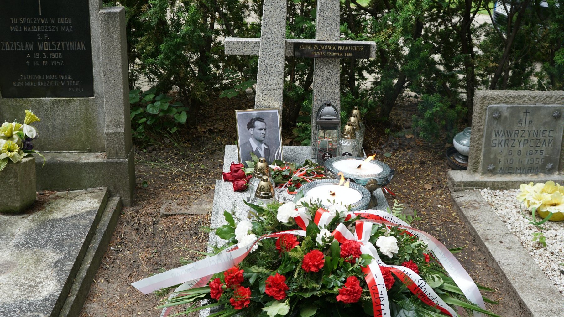 Zdjęcie przedstawia grób, na którym znajdują się kwiaty, znicze i zdjęcie.