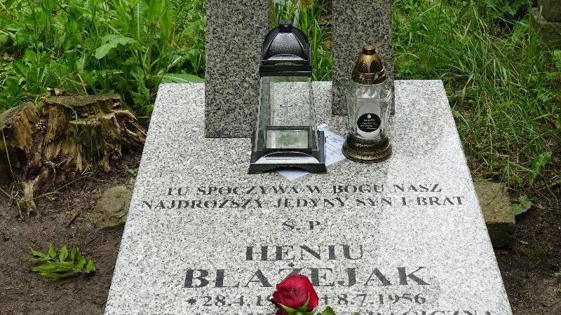 Zdjęcie przedstawia grób, na którym stoją znicze i leżą kwiaty.