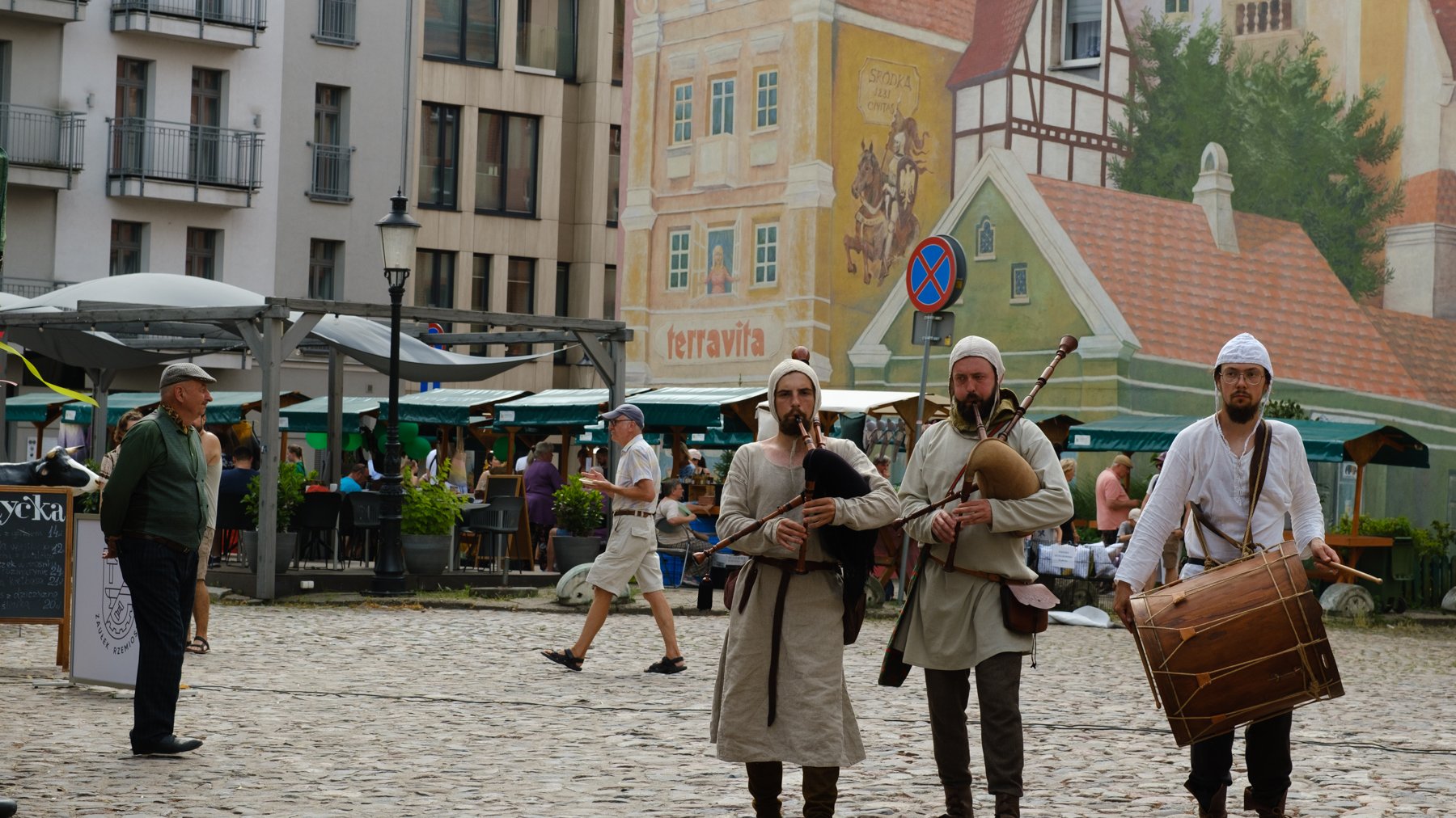 Targ Śródecki, widoczni na pierwszym planie są dudziarze, w tle mural oraz stoiska targowe