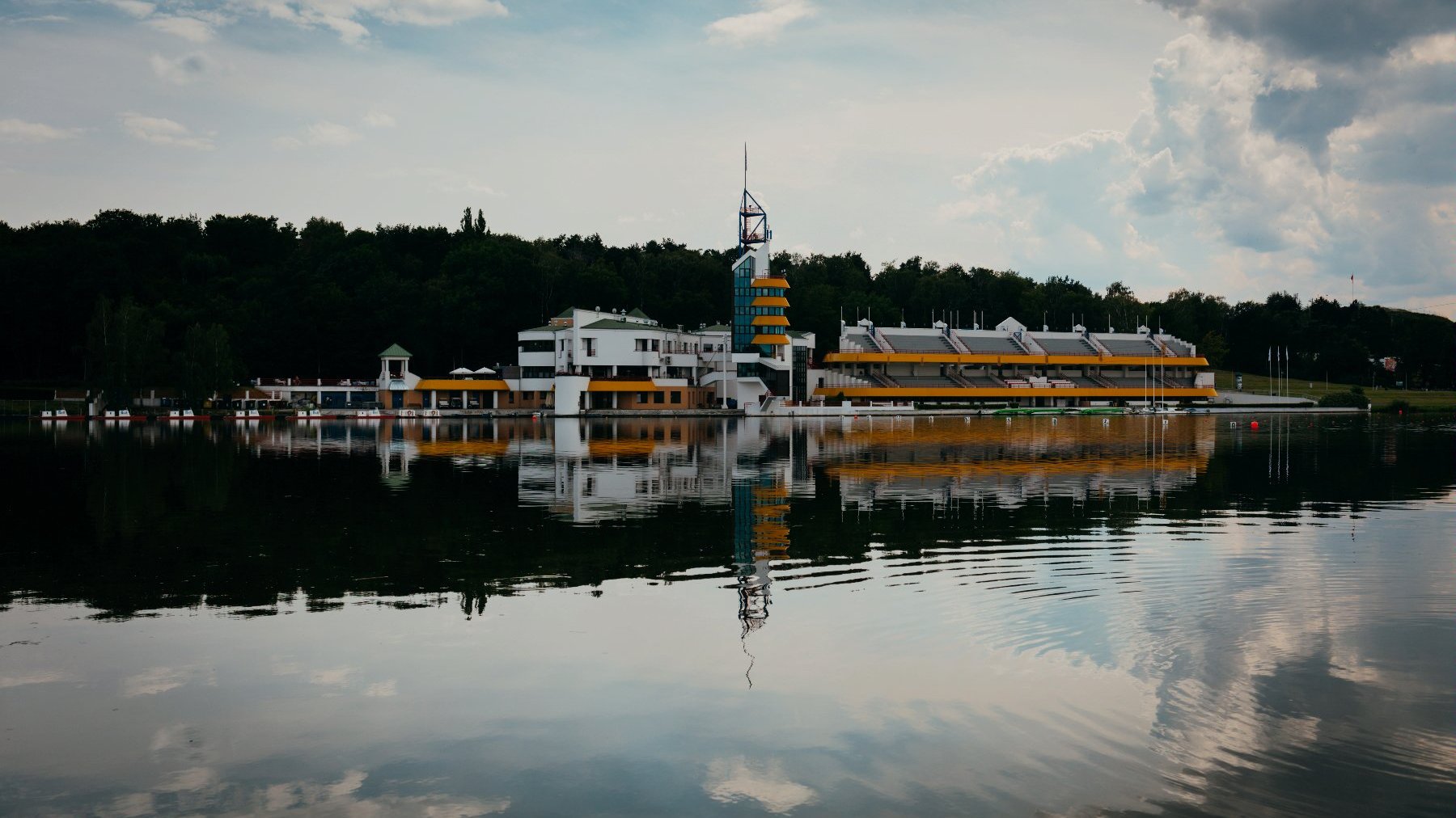 Zdjęcie przedstawia fragment Jeziora Maltańskiego oraz trybuny i wieżę sędziowską zespół sportowo-rekreacyjnego.