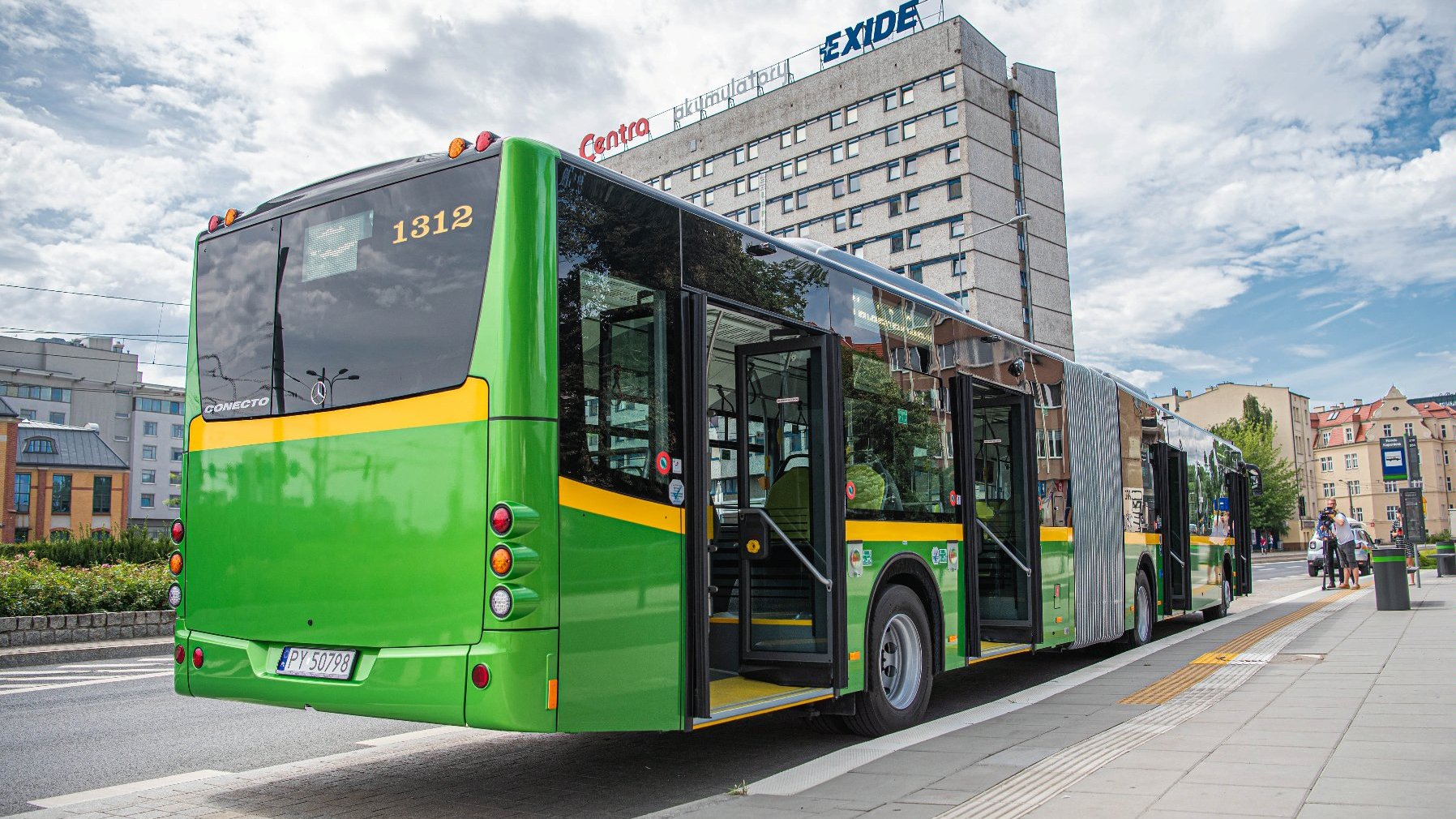 Na zdjęciu autobus stojący na przystanku, widziany od tyłu