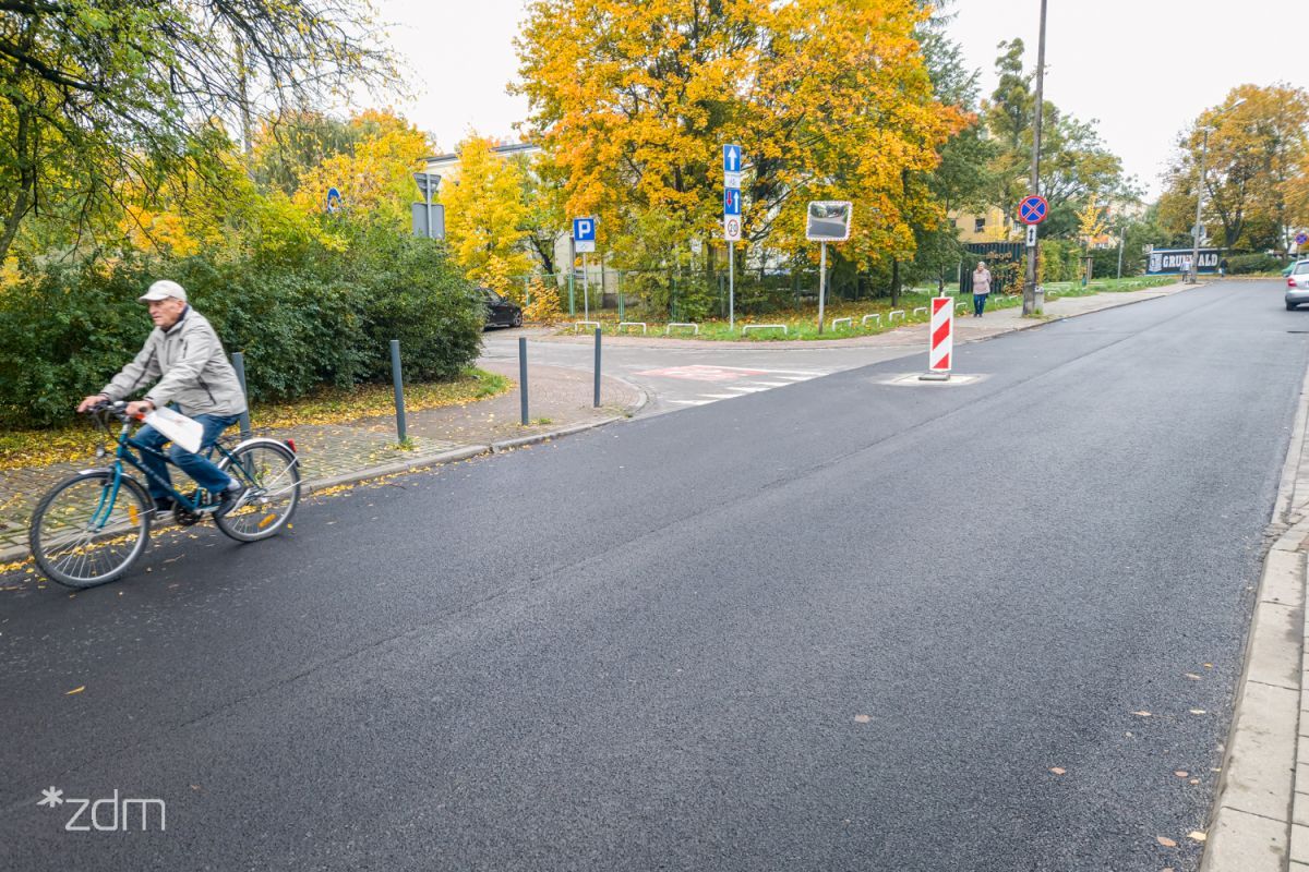 Zdjęcie przedstawia jezdnię, po której porusza się rowerzysta. W tle drzewa. - grafika artykułu