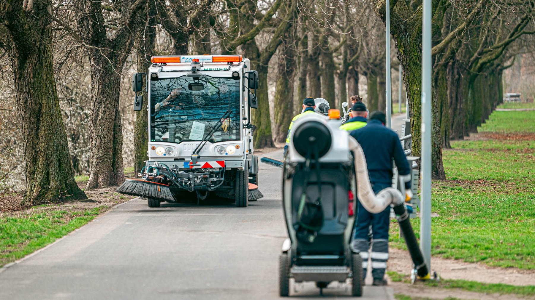 Zdjęcie przedstawia samochód i ludzi sprzątających Wartostradę.