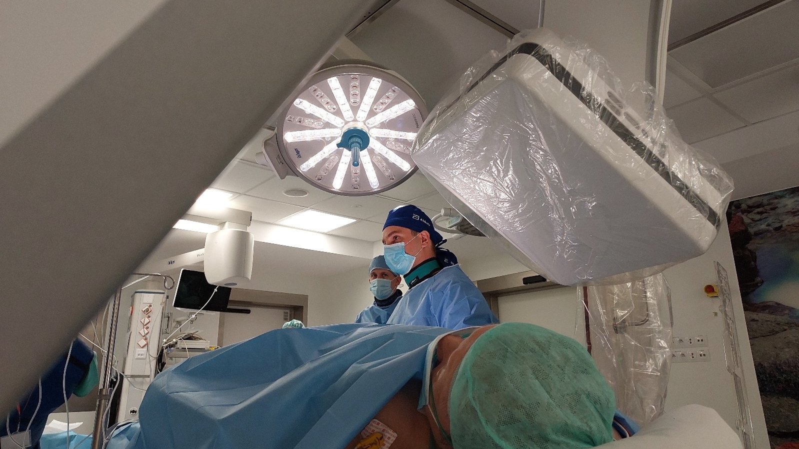 Na zdjęciu sala operacyjna, na pierwszym planie pacjentka, nad nią lekarze