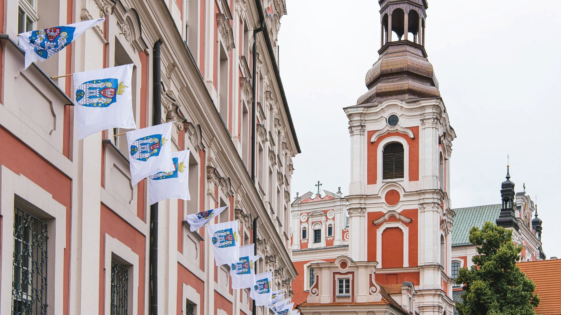 Zdjęcie przedstawia flagi z herbem miasta zawieszone na urzędzie.