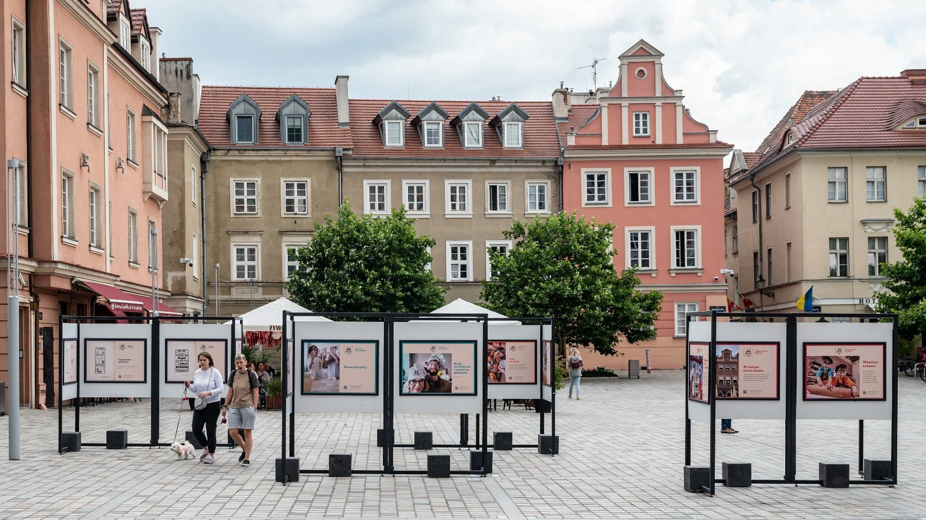 Zdjęcie przedstawia wystawę plenerową poświęconą Rogalowemu Muzeum Poznania na pl. Kolegiackim.