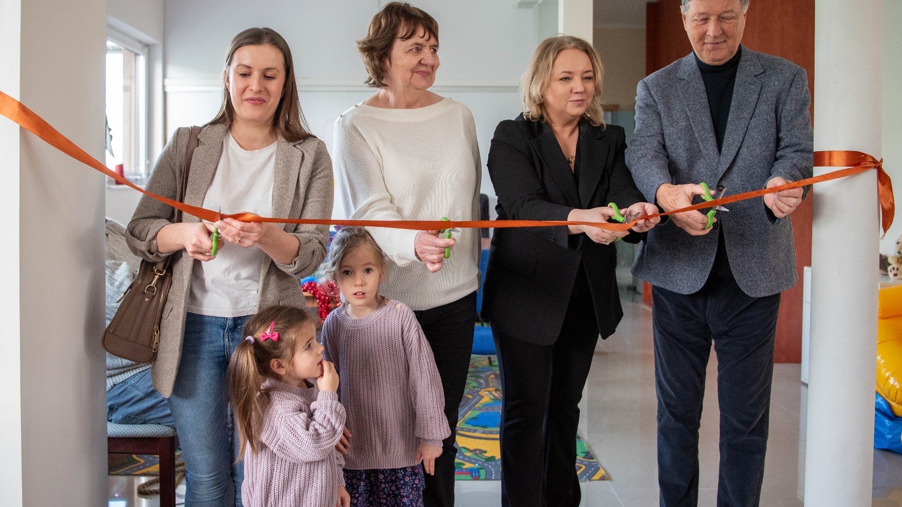 Na zdjęciu grupa ludzi przecinających wstęgi w pomieszczeniu