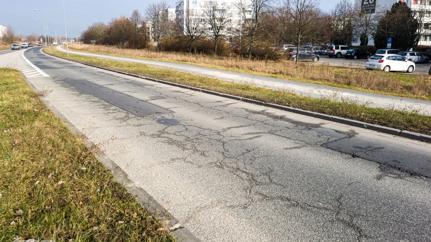 Zniszczona nawierzchnia ul. Szeligowskiego. W oddali widać parking i bloki na os. Stefana Batorego